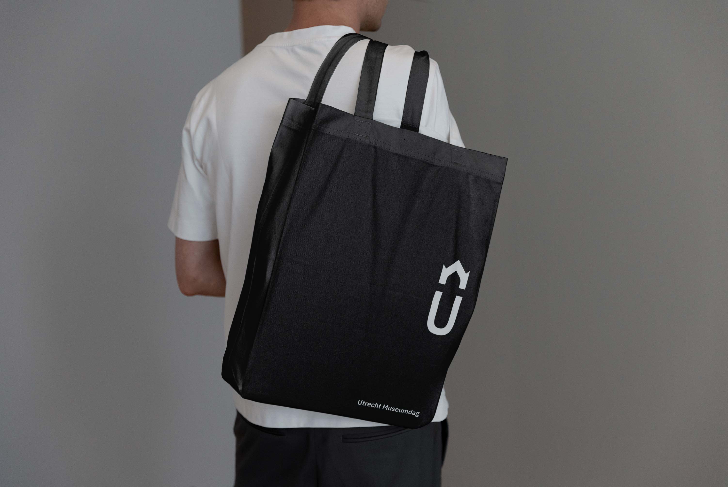 A man carrying a tote bag with the Utrecht Museumdag logo printed on it