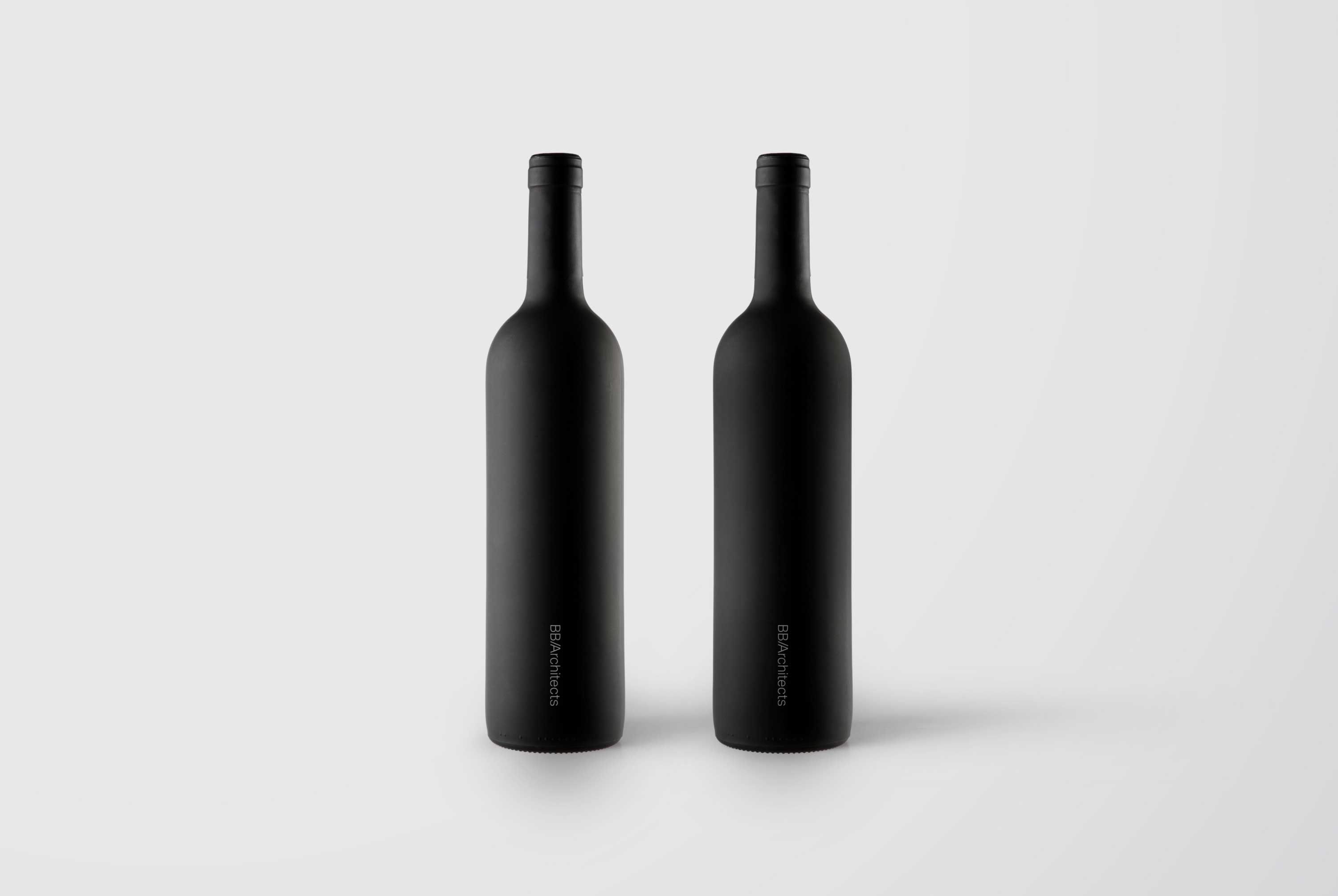 Two black wine bottles with the BB/Architects logo on them