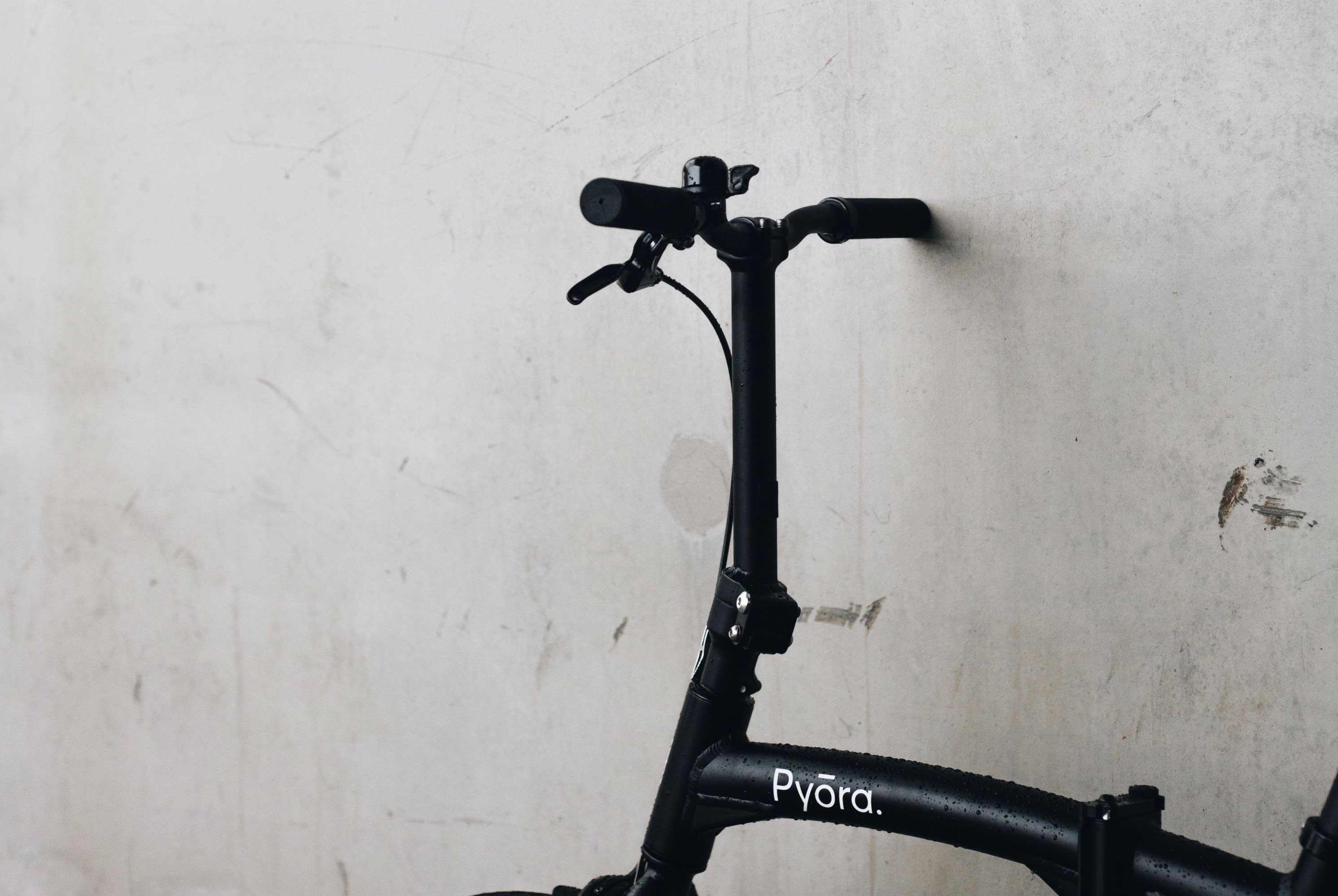 Black Pyora bike parked against a grey wall