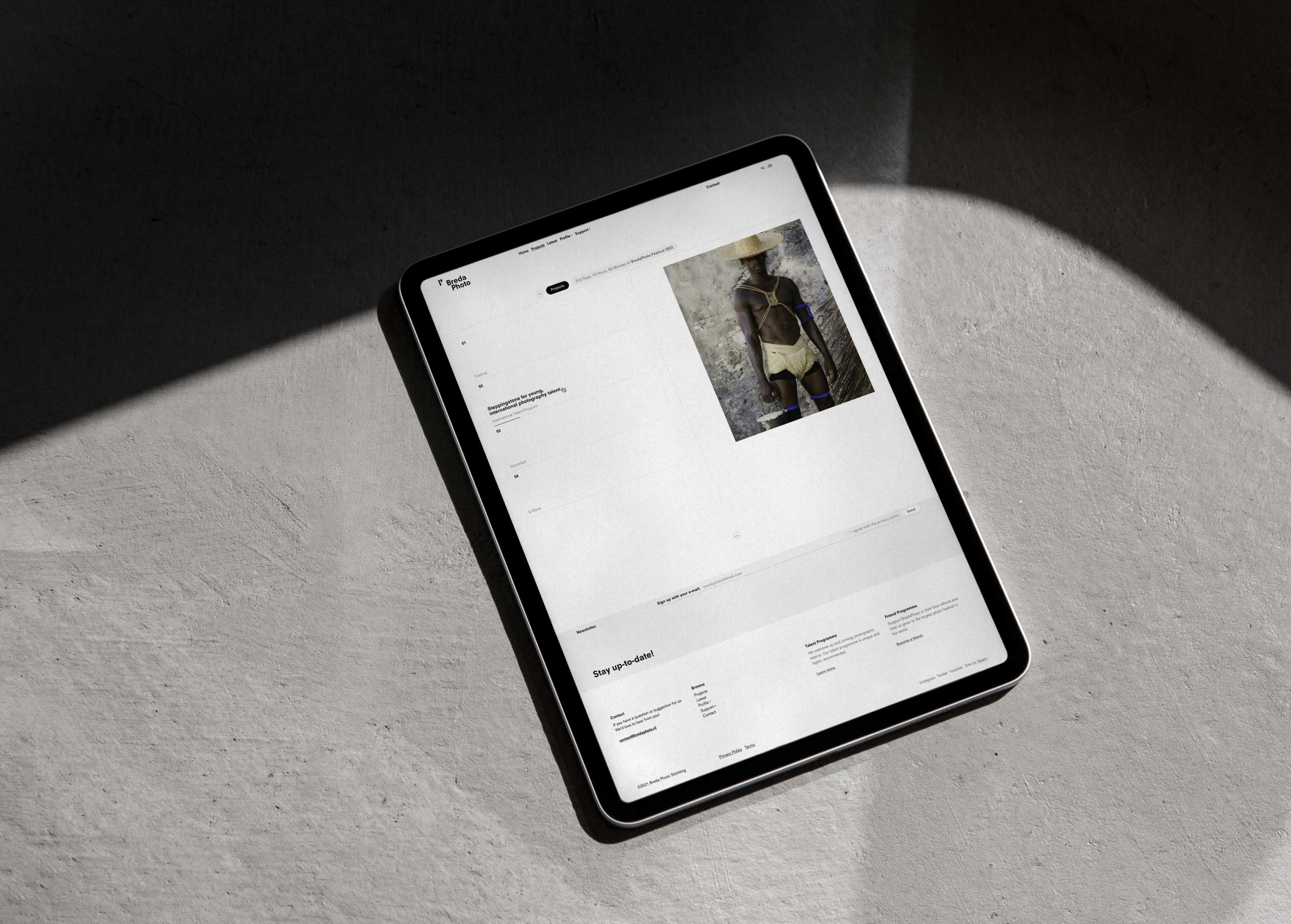 A tablet on a concrete floor displaying the BredaPhoto website